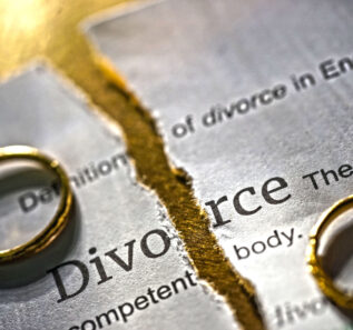 Torn paper with the definition of the word Divorce. On top of the paper are two rings