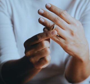 A woman wearing white shirt who is about to remove her wedding ring