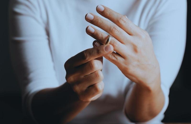 A woman wearing white shirt who is about to remove her wedding ring