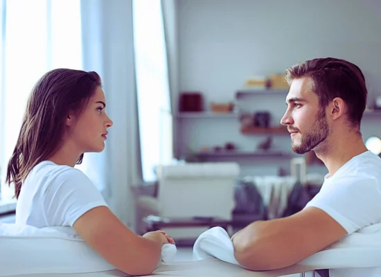 Couple talking sitting on a couch and looking each other at home. Divorce in Illinois While Living Together