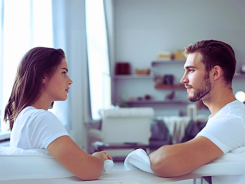 Couple talking sitting on a couch and looking each other at home. Divorce in Illinois While Living Together